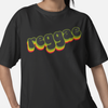 A person wearing a black short-sleeve T-shirt with the word 'reggae' printed across the chest in a retro 3D-style font with yellow, green, and red shadowing.