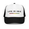 Black and white trucker hat featuring front 3D embroidered "life is irie" text and Reggae stripe in red, gold, green. Mesh back with adjustable closure.  